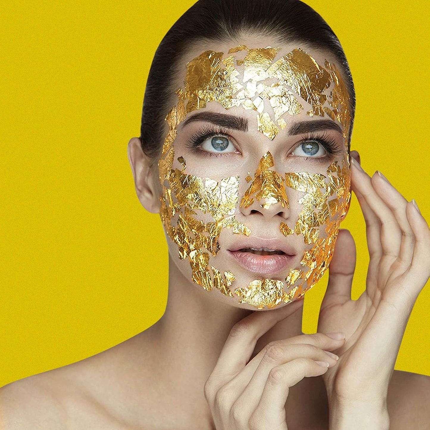 Woman wearing a gold face mask against a yellow background